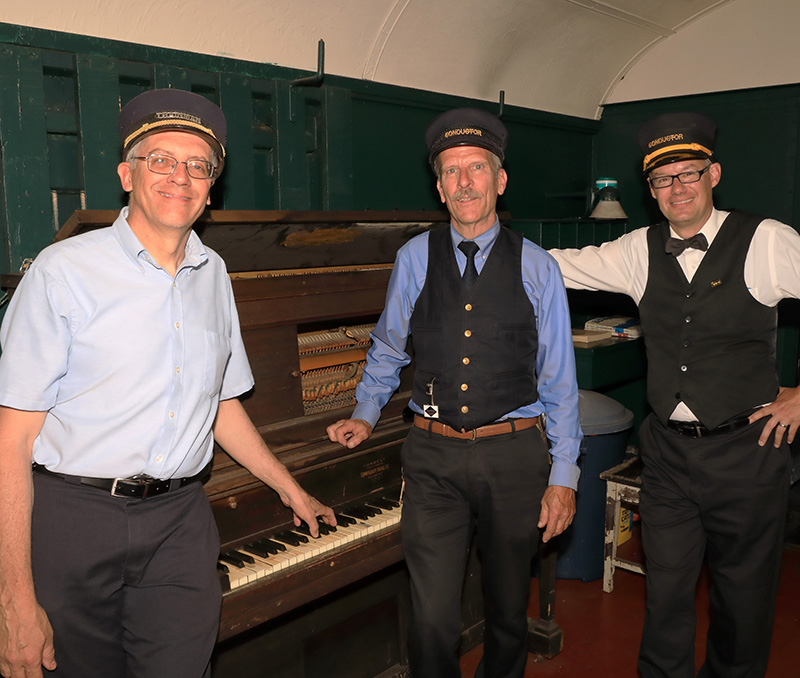 Three Conductors with a piano during a special train ride that the Wanamaker, Kempton & Southern railroad